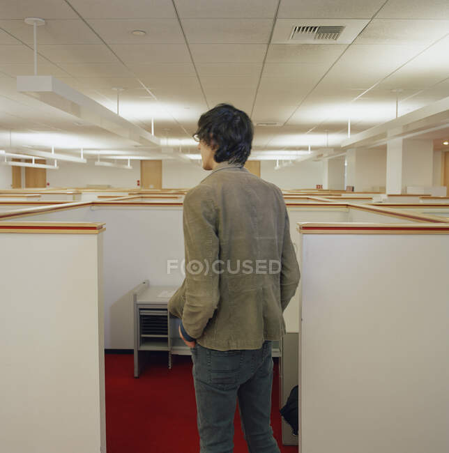 Jovem olhando sobre cubículos de escritório vazios — Fotografia de Stock