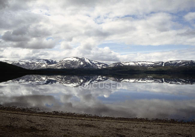 Красивый вид на озеро с отражением заснеженных гор — стоковое фото