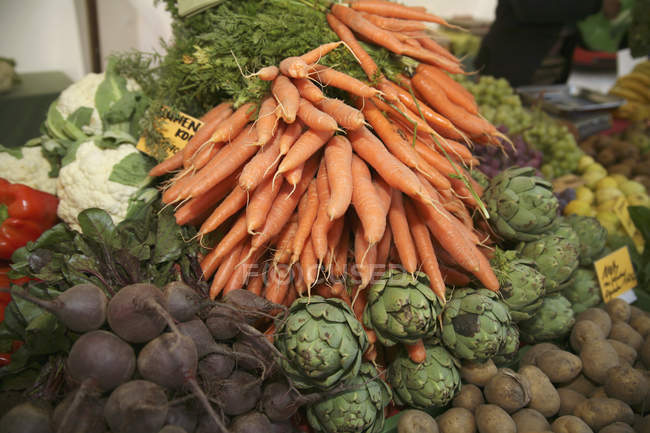 Vista de cerca de la pila de zanahorias en varias verduras en el mercado - foto de stock