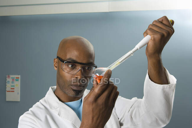 Técnico que mide la muestra con pipeta - foto de stock