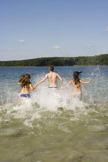 Gruppo di amici che corrono nel lago — Foto stock