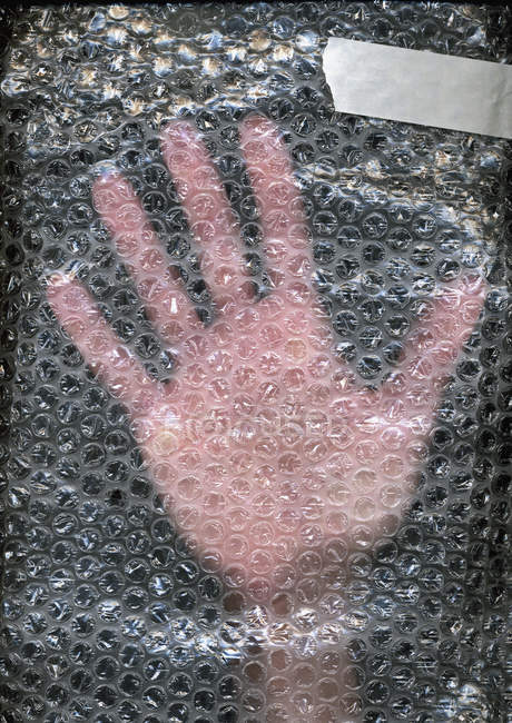Human hand behind plastic bubble wrap — Stock Photo