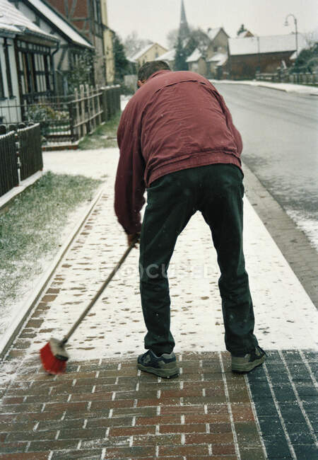 Man sweeping snow on sidewalk — Stock Photo