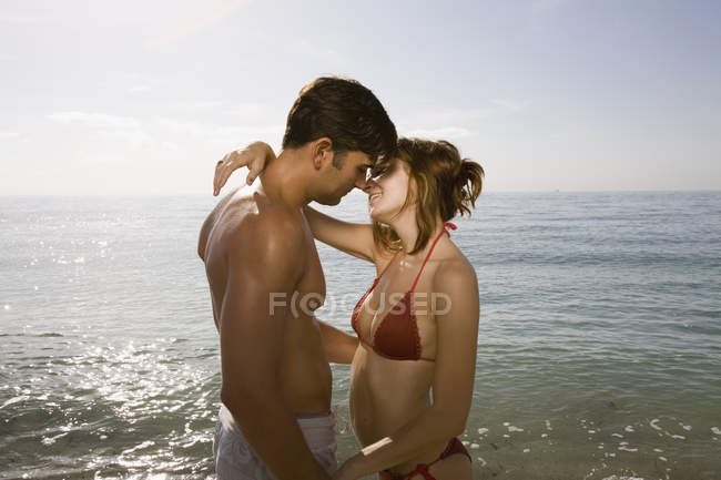 Couple embrasser dans l'eau de mer à la lumière du soleil — Photo de stock