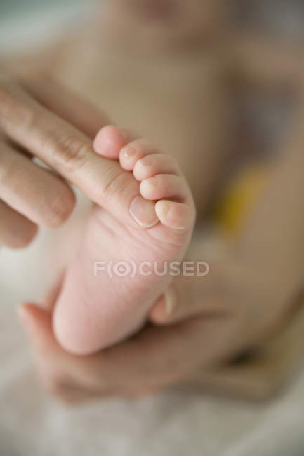 Madre tocando el pie del bebé - foto de stock