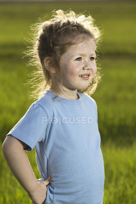A young girl standing in a field and looking away — Stock Photo