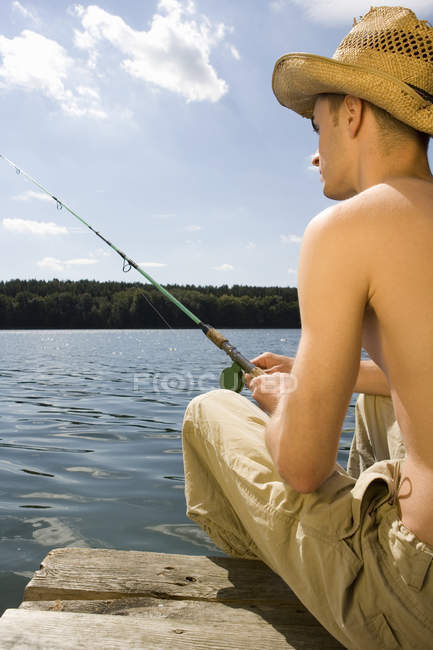Молодой человек рыбачит в озере — стоковое фото