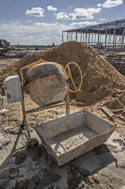 Cement mixer and sand heap at construction site — Stock Photo