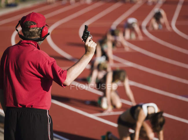 Rear view of race official holding starting gun at beginning of track event — Stock Photo