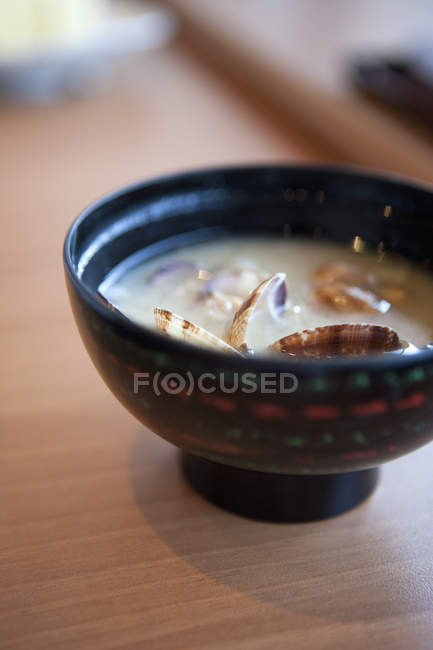 Vista de cerca del tazón con sopa de almeja en la mesa - foto de stock