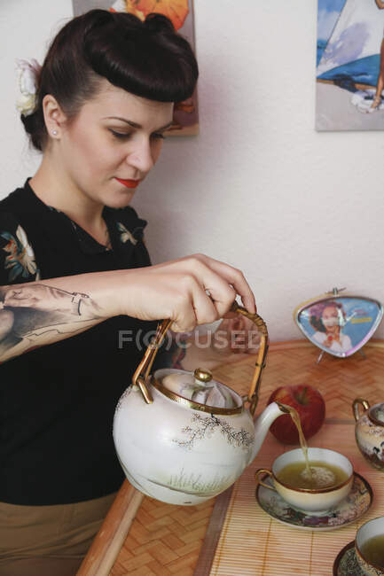 Young rockabilly woman pouring tea — Stock Photo