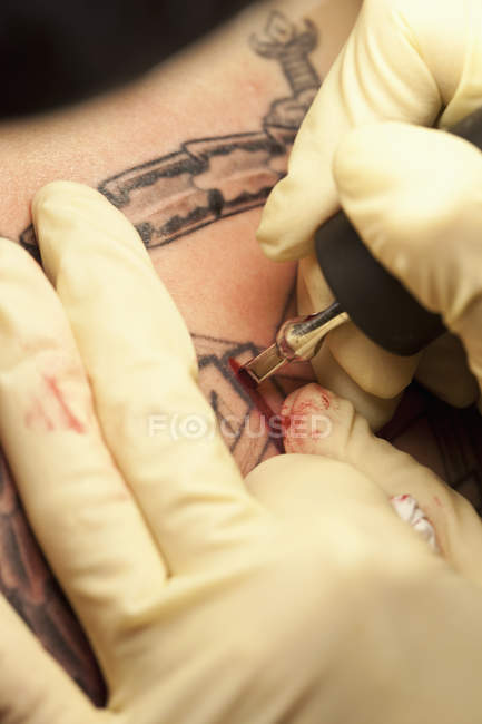 Close-up of a tattoo artist tattooing a design on human skin — Stock Photo