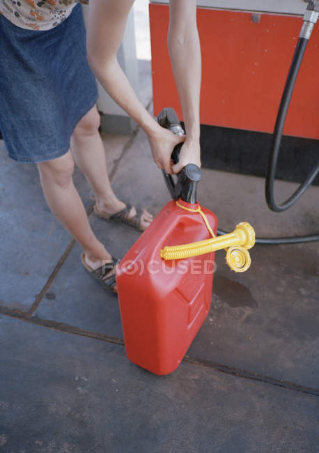 Mujer llenando latas de gasolina en gasolinera
, - foto de stock