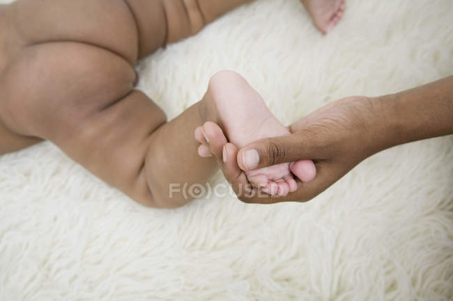 Cosecha mano femenina sosteniendo el pie del bebé - foto de stock