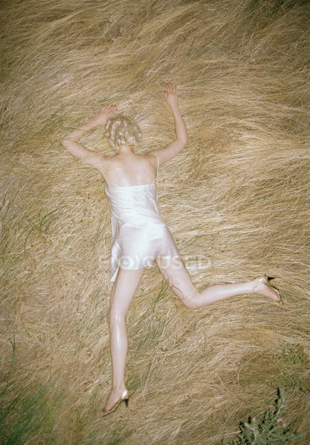 Rear view of blonde woman lying in straw — Stock Photo