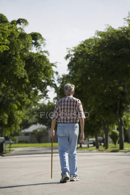 Rear view of senior man walking along street — Stock Photo