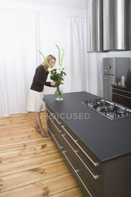 Eine Frau arrangiert Blumen in der Küche — Stockfoto