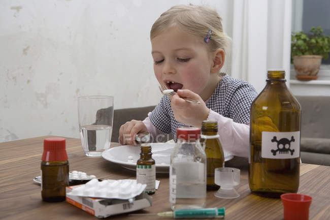 Молода дівчина, їдять таблетки, оточений лікарських засобів — Stock Photo