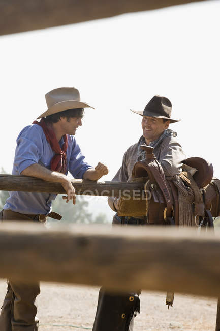 Two ranchers talking next to a fence — Stock Photo