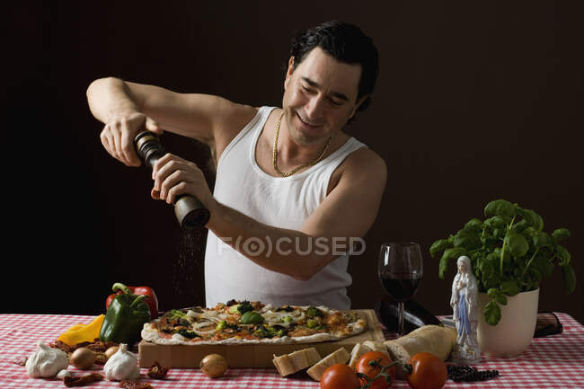 Стереотипичный итальянец, использующий перцовую мельницу на своей пицце — стоковое фото