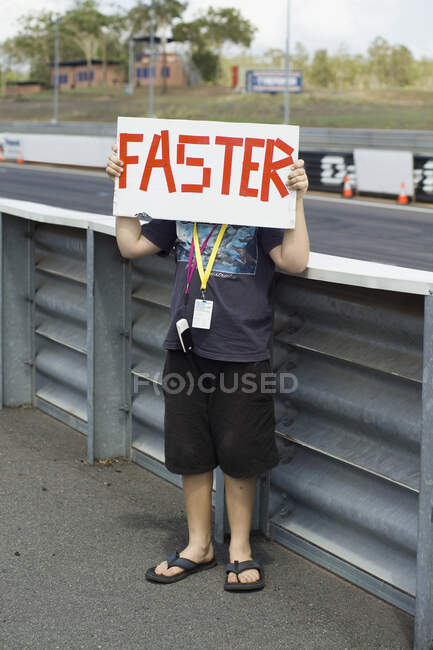A boy holding a 'Faster' sign — Stock Photo