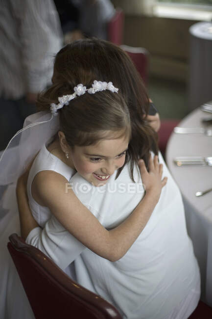 Молода дівчина у своєму святому товариському вбранні обіймає маму. — стокове фото