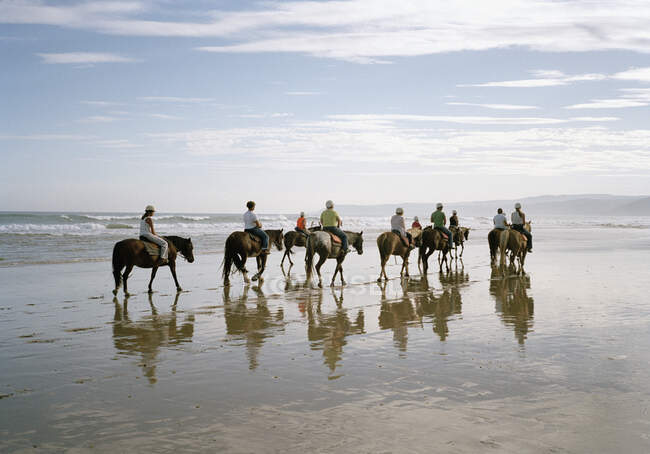 Un groupe de personnes à cheval sur une plage — Photo de stock