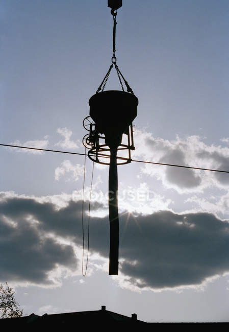 Silhouette of  concrete pourer suspended from crane — Stock Photo