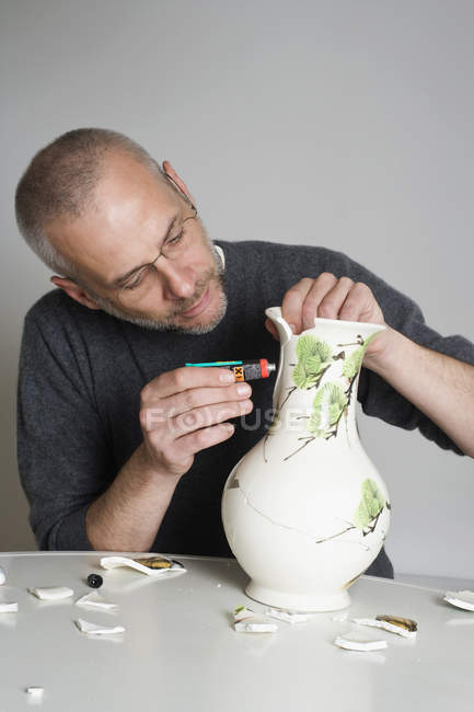 Ein Mann repariert eine kaputte Vase — Stockfoto