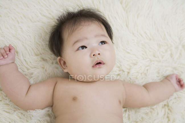 A baby lying down on a rug — Stock Photo