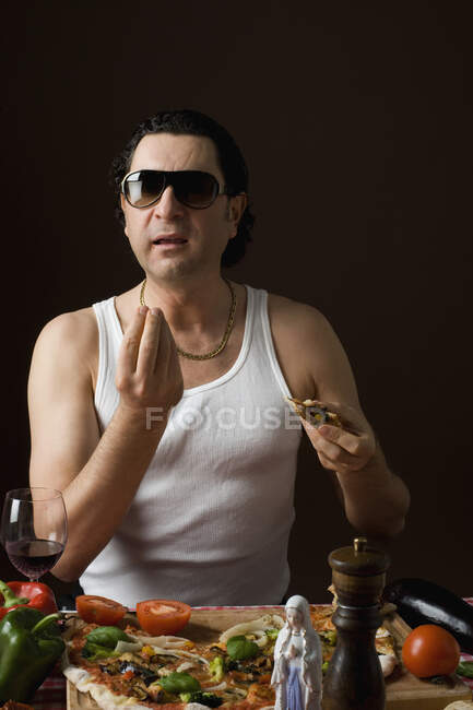Hombre italiano estereotipado comiendo pizza y haciendo gestos con la mano - foto de stock