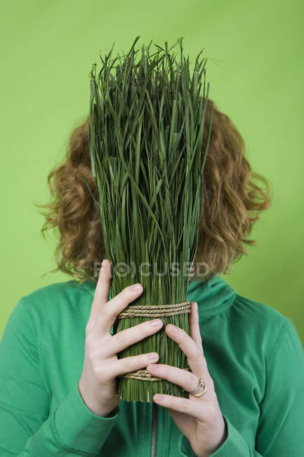 Femme tenant un bouquet attaché d'herbe coupée devant le visage — Photo de stock