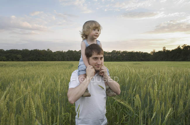 Um homem carregando uma criança em seus ombros — Fotografia de Stock