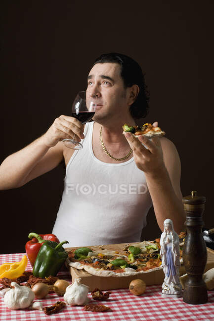 Hombre italiano estereotipado sosteniendo una copa de vino y comiendo pizza - foto de stock