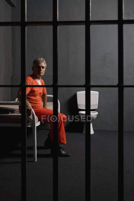 focused_179772674-stock-photo-prisoner-sitting-bed-prison-cell.jpg