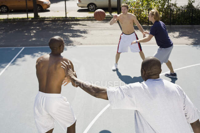 Четверо мужчин играют в баскетбол — стоковое фото