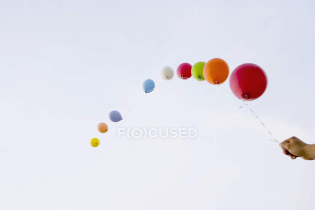 Crop hand holding helium balloons tied to string — Stock Photo