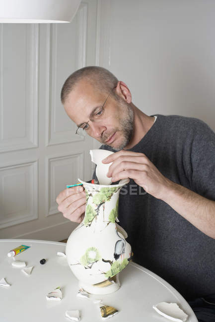 Ein Mann repariert eine kaputte Vase — Stockfoto