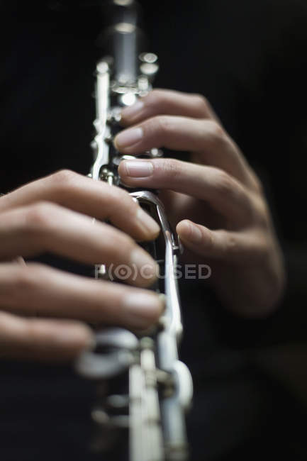 Manos de corte tocando clarinete sobre fondo negro — Stock Photo