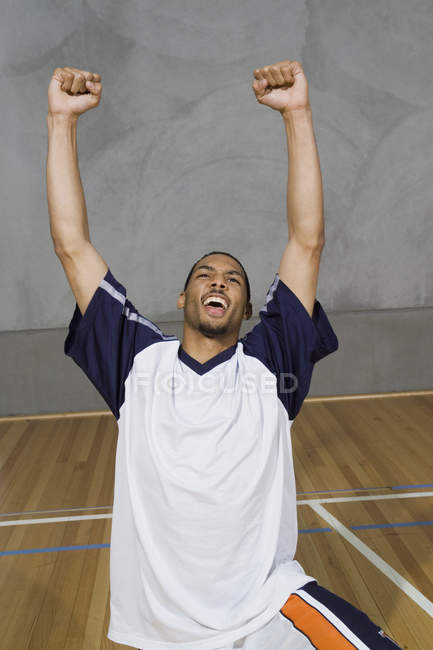 Un giovane inginocchiato con le braccia alzate in vittoria — Foto stock