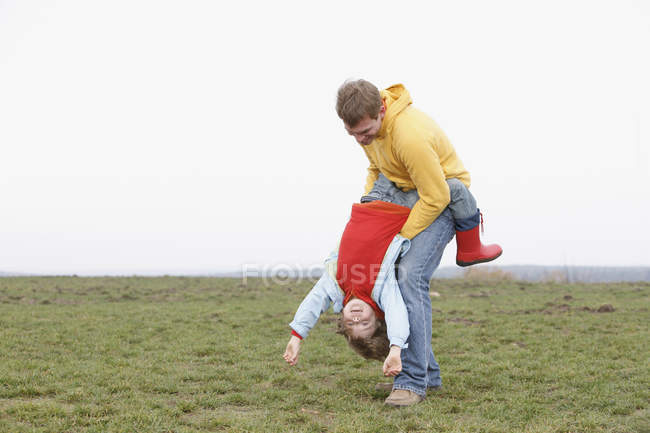 Ein Mann hält einen Jungen kopfüber in einem Park — Stockfoto