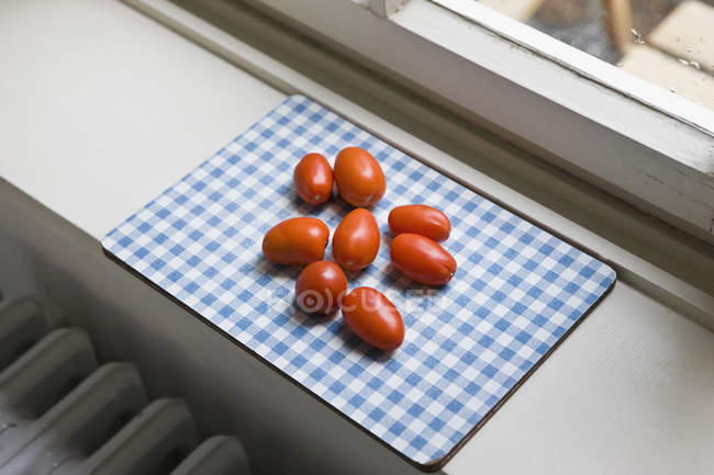 Cherry tomatoes on cutting board at window sill — Stock Photo