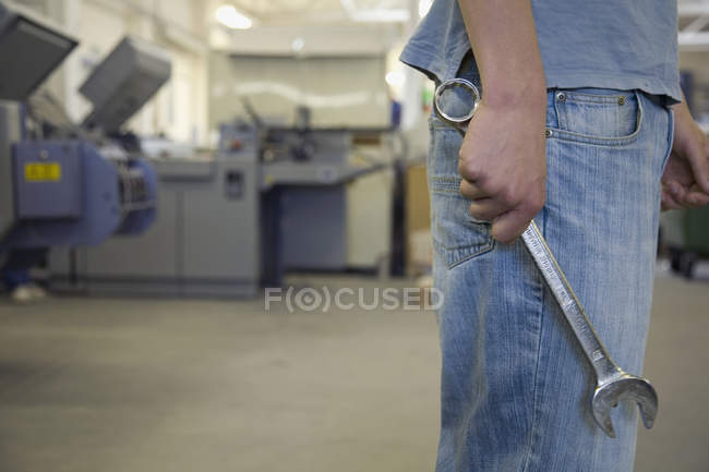 Midsection of man standing in factory with wrench — Stock Photo