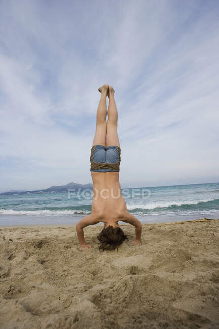 Vue arrière d'un garçon faisant un appui-tête sur une plage — Photo de stock