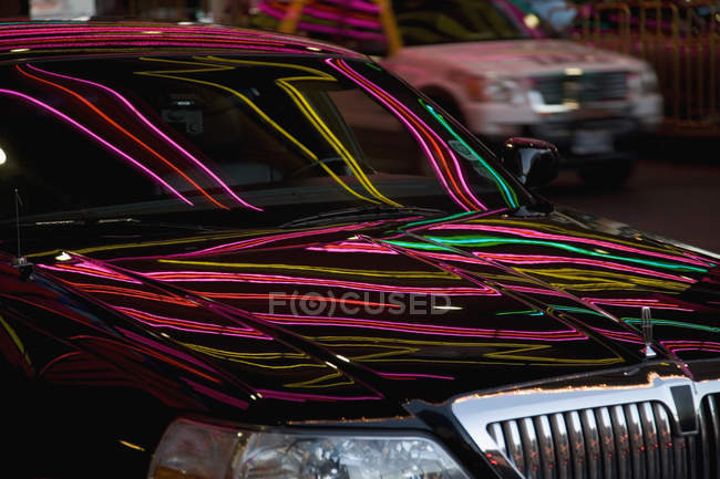 Cropped image of limousine reflecting neon lights — Stock Photo