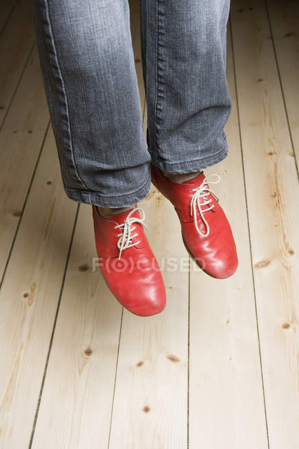 Low section of woman wearing red shoes in mid-air — Stock Photo