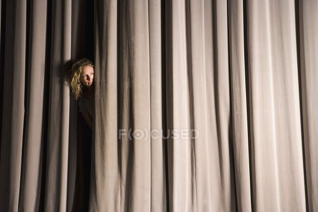 Женщина, заглядывающая через занавеску — стоковое фото