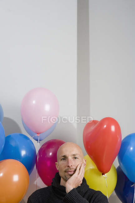 Hombre sentado entre globos - foto de stock