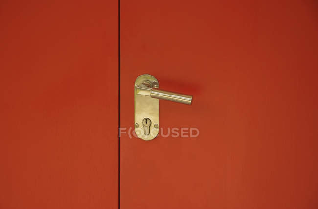 Деталь ручки золотой двери на красной двери — стоковое фото