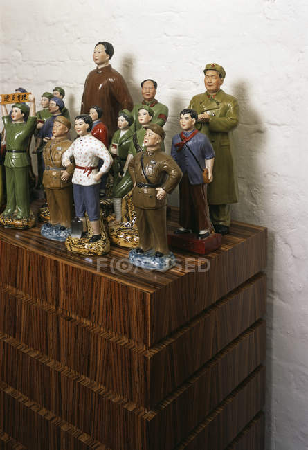 Communist ceramic figurines arranged on wooden cabinet — Stock Photo